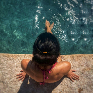 woman sitting poolside with feet in the water