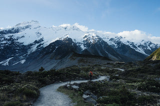 Person hiking on a trail with snow-capped mountains in the background