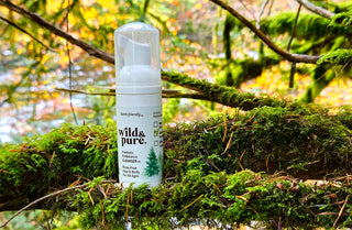 Wild & Pure travel size EcoBalance Cleanser sitting among tree branches with water in the background