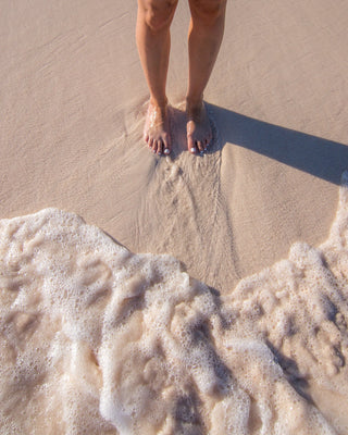 Woman's feet in sand as the tide comes in