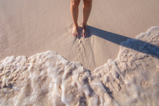 Woman's feet in sand as the tide comes in
